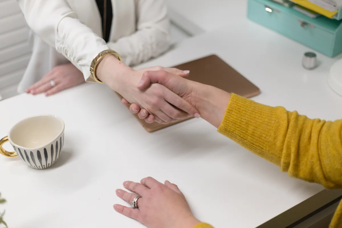 A handshake across a desk after agreeing a partnership